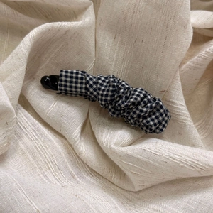 Detail of Gingham fabric banana hair clip with pleated design on beige cloth background