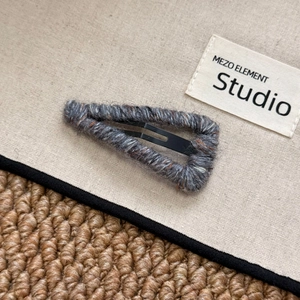 Macro shot of knitted wool texture on a triangular metal snap hair clip for styling