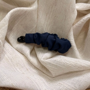 Close-up of navy blue pleated fabric banana clip showing detailed textile texture and design