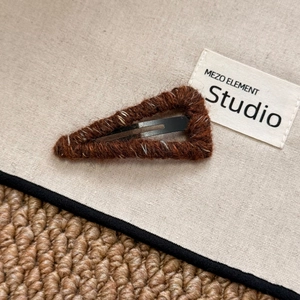 Close-up of vintage brown knit triangular hair clip showing retro wool texture detail