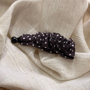 Detailed close-up of brown polka dot fabric banana clip with elegant pleated texture