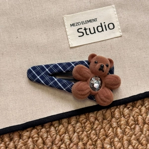 Detailed view of navy blue plaid hair clip with a brown flocking bear and clear rhinestone