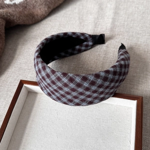 Close-up of retro brown plaid fabric headband with textured finish on linen background
