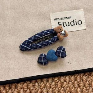 Close-up of navy plaid fabric hair clips with a cute flocked bear and heart patterns