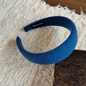 Detail of dark blue woolen headband showing handmade label on plush background