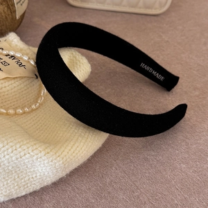 Detail view of handmade black sponge headband with soft velvet texture and inner lettering