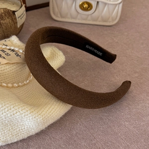 Detail of a brown thick sponge headband with a handmade label and soft matte texture