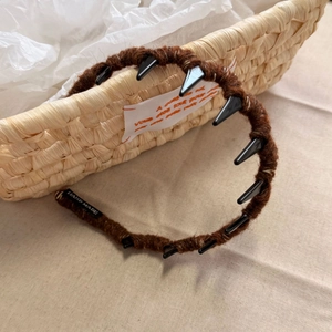 Close-up of brown plush headband with black teeth combs and hand made label detail
