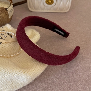 Detailed view of a handmade burgundy velvet sponge headband with a soft artisan label