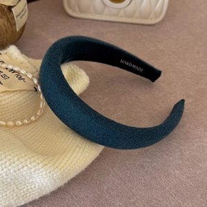 Close-up of handmade dark green sponge headband with soft velvet texture on fabric