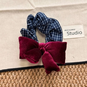 Navy blue plaid scrunchie with a velvet wine red bow hair tie in a top view shot
