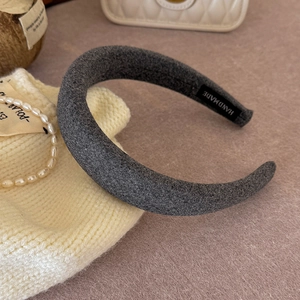 Detail showing high-crown grey sponge headband with textured fabric and handmade label