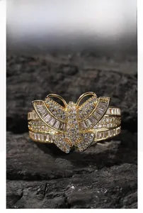 Macro shot of gold butterfly ring with cubic zirconia on black carbon texture