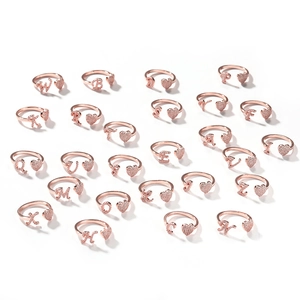 Vista dettagliata di 26 anelli iniziali in oro rosa con forme a cuore e micro-intarsio scintillante