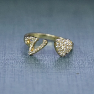 Dettaglio dell'anello regolabile in oro con lettera V e cuore in pavé di zirconi