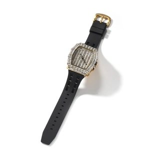 Macro shot of iced out gold square watch dial with baguette stones and black silicone strap