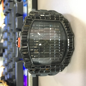 Close-up of black square iced-out watch with crystal bezel and orange crown detail