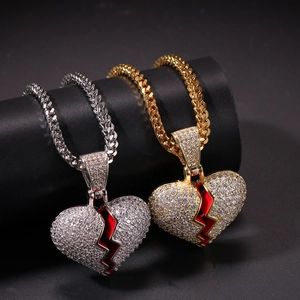 Macro view of gold and silver broken heart pendants with inset zircons and red enamel