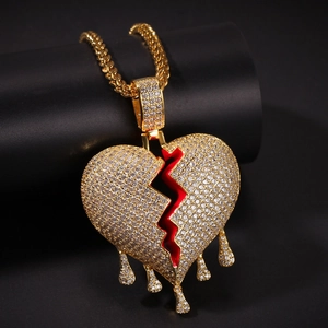 Macro shot of hip-hop heart pendant with white crystals and red enamel on golden chain