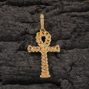 Macro detail of iced-out gold Ankh cross pendant with cubic zirconia on black wood