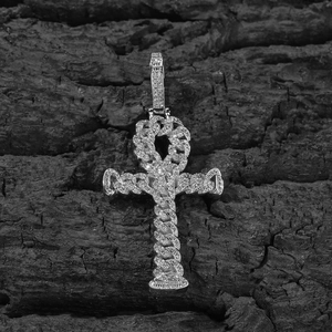 Macro detail of silver iced out Ankh cross pendant with cubic zirconia on black wood