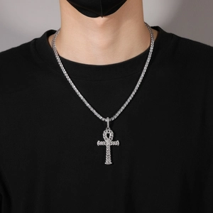 Iced out Ankh cross pendant on silver tennis chain worn over a black shirt