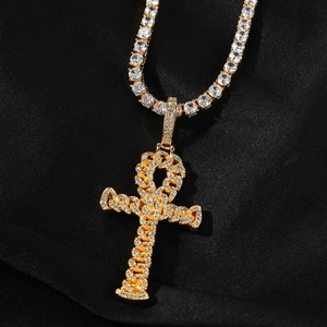 Macro view of gold Ankh cross pendant with pave-set zircons on black silk background