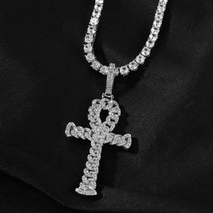 Close-up of iced out silver Ankh cross pendant with tennis chain on black silk fabric