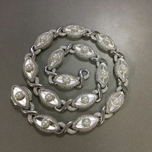 Detail van oogvormige zilveren schakels met witte parels en sprankelende pavézetting