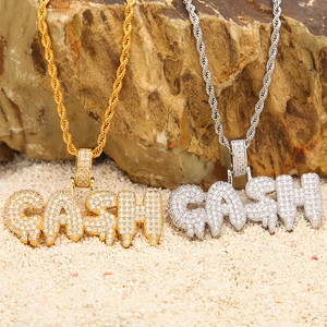 Detailopname van gouden en zilveren CASH-hangers met zirkonia en touwketting in hiphopstijl