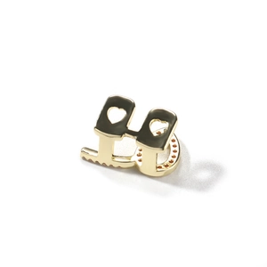 Detail of single gold plated hip hop grillz with heart cut-outs and red paved crystals