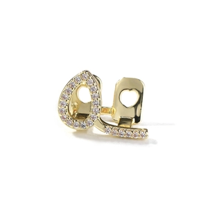 Macro shot of gold-plated pear-shaped hip hop grillz with pavé crystals and heart cutout