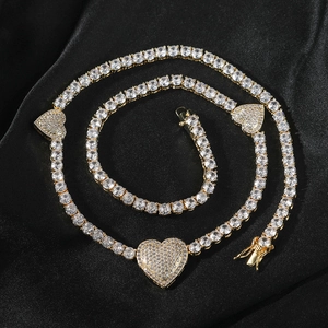 Detail van gouden hart tennis ketting met pavé zirkonia op een zwarte satijnen ondergrond