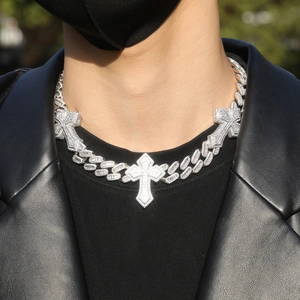 Silver Cuban link chain with three iced-out cross pendants worn on a black jacket