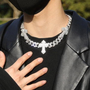 Close-up of silver Cuban link necklace with three iced-out cross pendants on a model