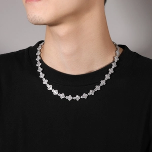 Detailed close-up of a silver-toned hip-hop cross necklace with cubic zirconia on a male model