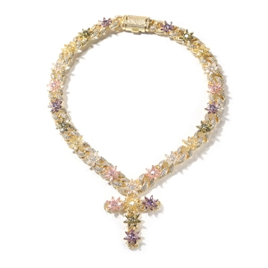 Macro detail of golden cross pendant with colorful zircon flowers on Cuban chain