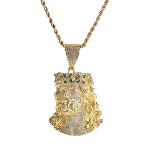 Détail du pendentif Jésus doré serti de zircons avec accents verts sur une chaîne torsadée