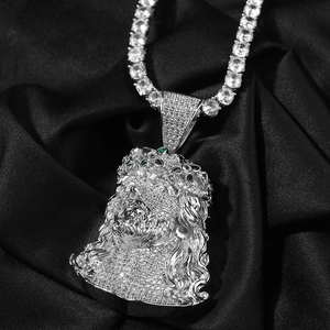 Macro d'un pendentif tête de Jésus avec pierres vertes sur une chaîne tennis