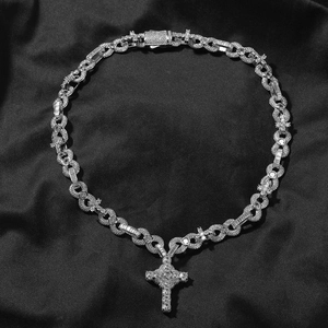 Macro view of iced out cross pendant and infinity chain on elegant black silk background