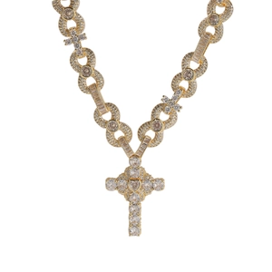Macro shot of gold-plated cross pendant necklace with white zircon pavé and heart center