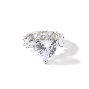 Vue macro d'une bague coeur en argent sertie de zircons sur un fond blanc neutre