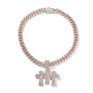 Macro view of iced-out triple cross pendant set on a Cuban link chain with two-tone finish