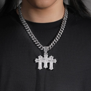 Close-up of silver Cuban link chain with three layered iced-out zircon cross pendants