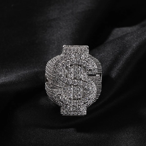 Macro shot of silver hip hop ring with iced-out dollar sign over black silk fabric