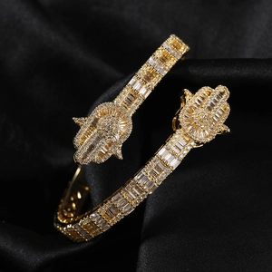 Macro shot of gold Hamsa Hand bracelet with pave white zircons on black satin