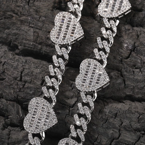 Macro shot of silver hip hop Cuban link chain featuring iced out heart shaped pendants