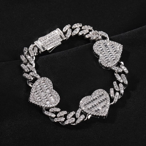 Detail view of silver Cuban link bracelet with three iced out heart charms on black silk
