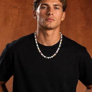Close-up of colorful gemstones and pearl necklace worn by a model against brown background