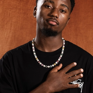 Detail of colorful gemstones and pearls necklace worn by male model on wooden backdrop